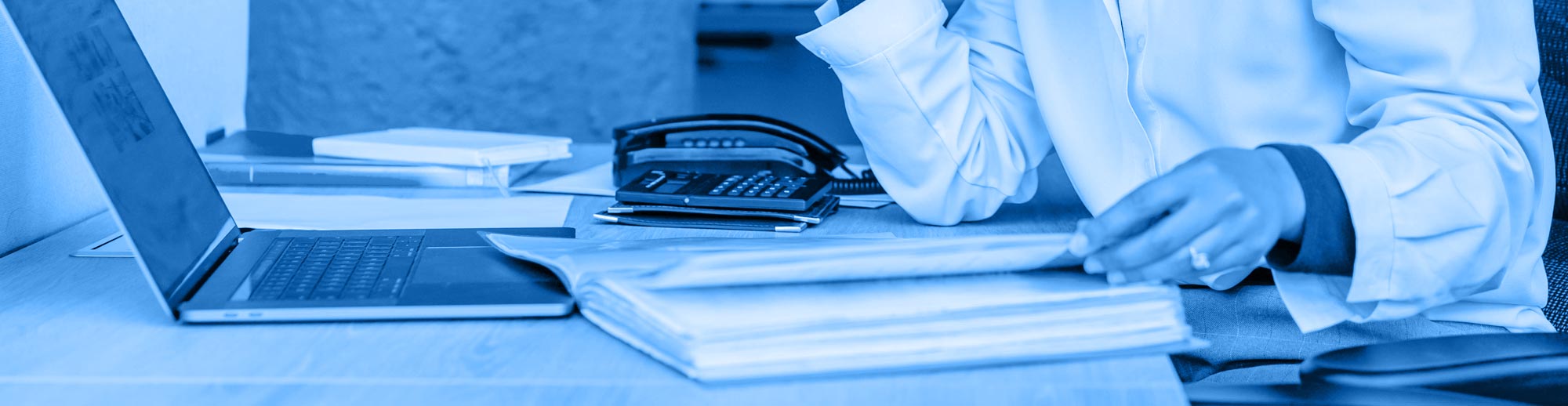 stock photo professional working at laptop hand and elbows only, all washed in monochromatic blue from the main logo