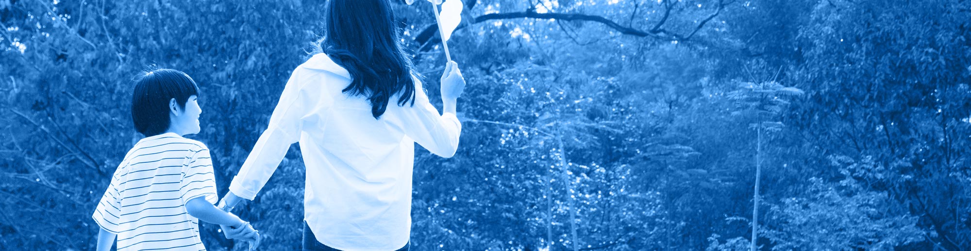 stock photo of woman and child seen from behind walking together in joy with forest in background, all washed in monochromatic blue from the main logo